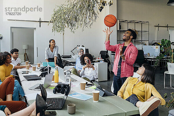 Geschäftsmann dreht Basketball von Kollegen im Büro