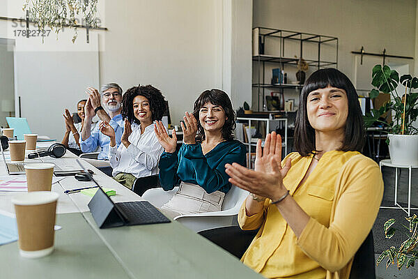Lächelnde  gemischtrassige Kollegen  die bei einem Treffen im Büro in die Hände klatschen