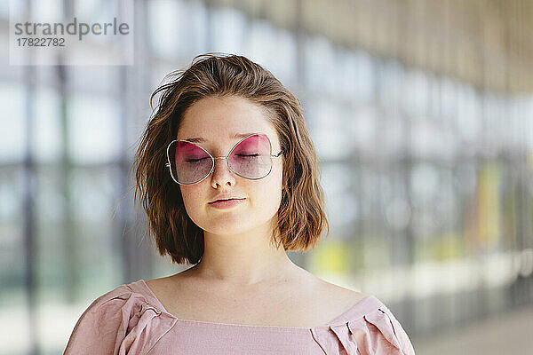 Teenagermädchen mit geschlossenen Augen und rosa Sonnenbrille