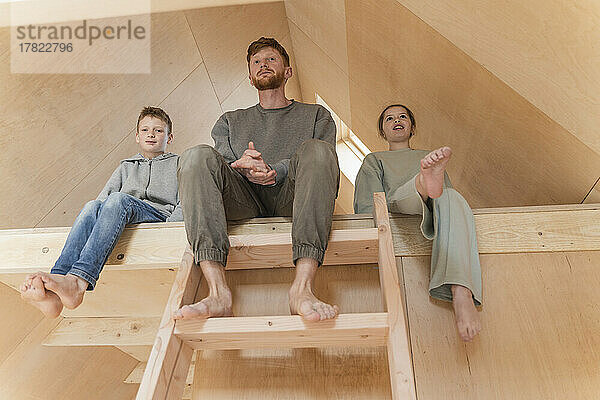 Father and kids sitting on the second floor ladder in eco house