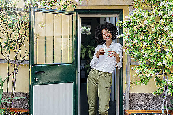 Lächelnde junge Geschäftsfrau  die vor der Tür Kaffee trinkt
