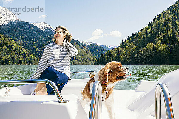 Glückliche Frau mit Hund auf dem Boot am Ritsa-See