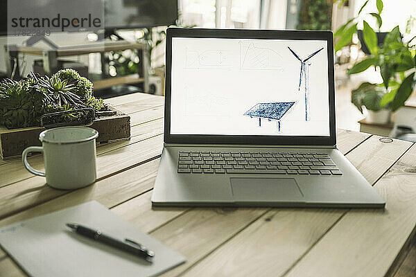 Solarpanel und Windkraftanlage auf dem Bildschirm des Laptops zu Hause