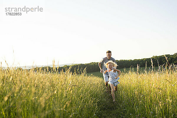 Verspielter Vater und Tochter laufen im Feld