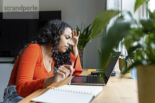 Gestresste Frau konzentriert sich auf die Arbeit mit Laptop im Heimbüro
