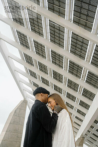Young man kissing woman on forehead standing under roof