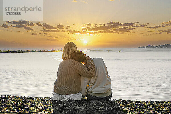 Mutter und Tochter genießen den Sonnenuntergang am Strand