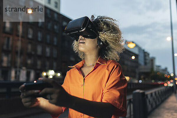 Frau hält Controller in der Hand und trägt nachts ein Virtual-Reality-Headset