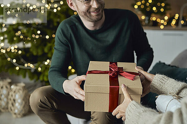 Lächelnder Mann  der Frau zu Hause ein Geschenk macht