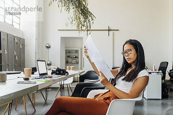 Junge Geschäftsfrau liest Papierdokumente im Büro