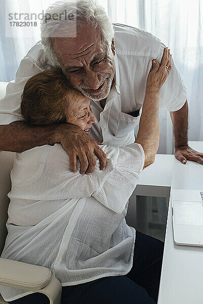 Glücklicher älterer Mann umarmt Mutter zu Hause