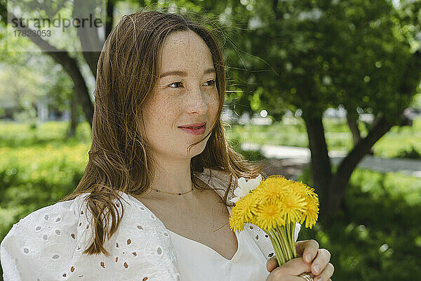 Lächelnde Frau mit Blumen im Park