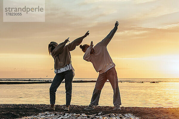 Teenage girl with mother doing dab standing at beach