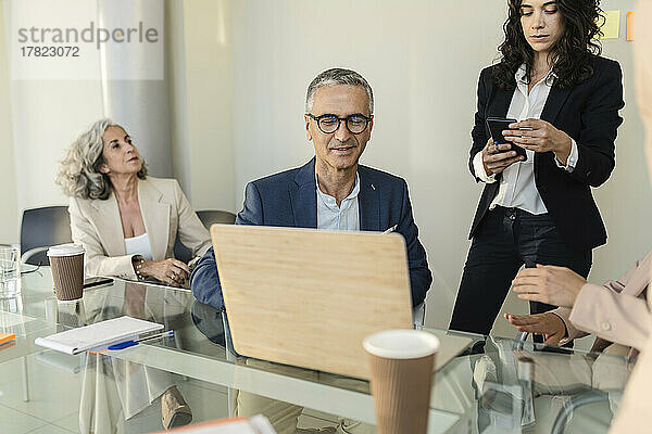 Geschäftsmann diskutiert am Laptop bei Treffen mit Kollegen im Büro