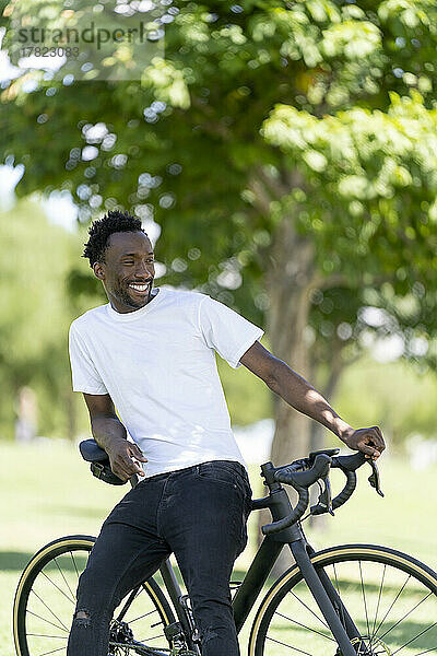 Lächelnder Mann sitzt auf dem Fahrrad im Park