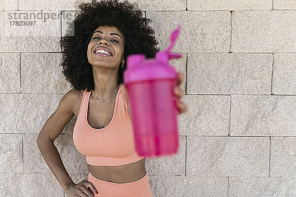 Lächelnde Afro-Frau zeigt Pick-Wasserflasche
