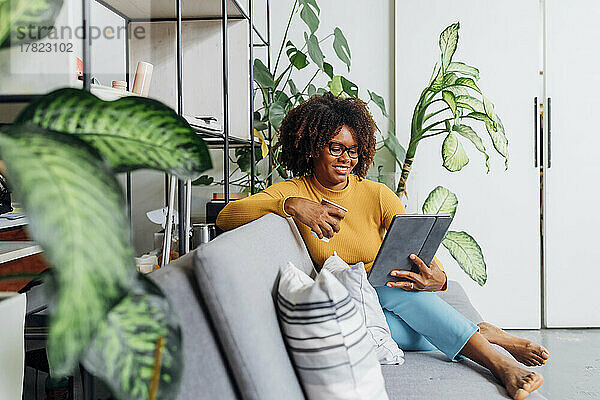 Lächelnde Geschäftsfrau benutzt Tablet-PC auf dem Sofa im Büro