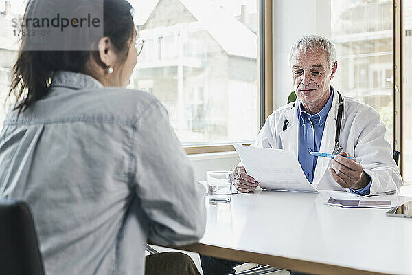 Doctor discussing with patient over document in medical clinic