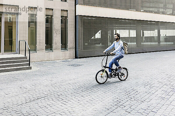 Lächelnder Mann fährt Fahrrad in der Stadt