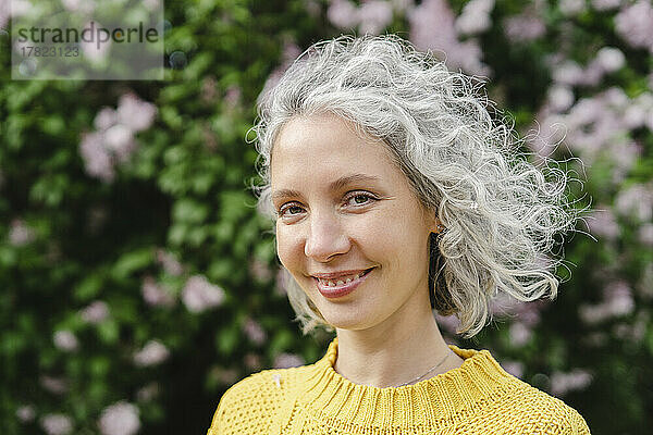 Glückliche Frau mit lockigen grauen Haaren im Park