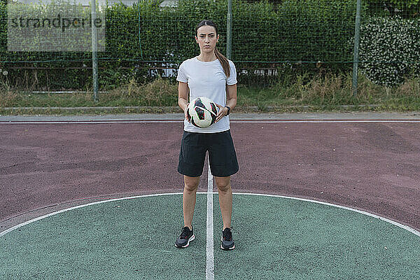 Junge Frau hält Ball im Fußballplatz