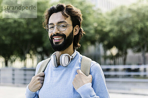 Glücklicher bärtiger Mann mit kabellosen Kopfhörern