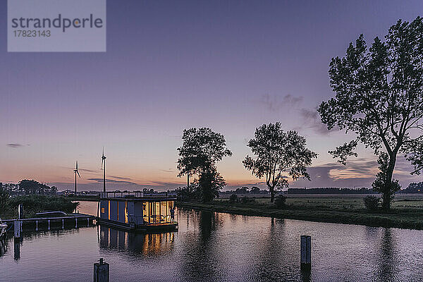 Beleuchtetes Hausboot auf dem Fluss Yser bei Sonnenuntergang