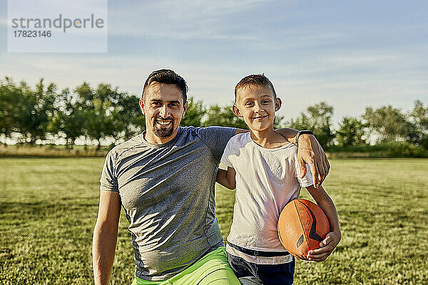 Glücklicher Vater und Sohn zusammen auf dem Sportplatz an einem sonnigen Tag