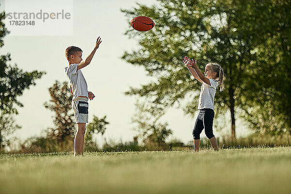 Bruder und Schwester werfen Rugbyball auf dem Sportplatz