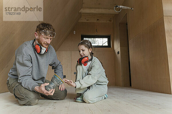 Vater und Tochter schleifen den Boden in ihrem neuen Öko-Haus