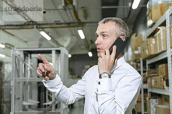 Geschäftsmann telefoniert in Fabrik mit Mobiltelefon