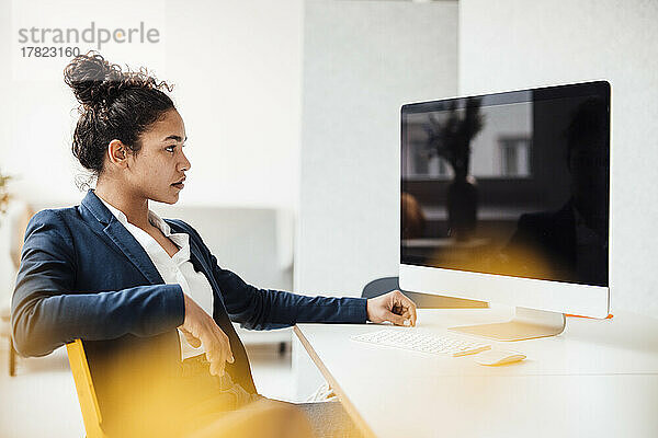 Geschäftsfrau mit Desktop-PC sitzt am Schreibtisch