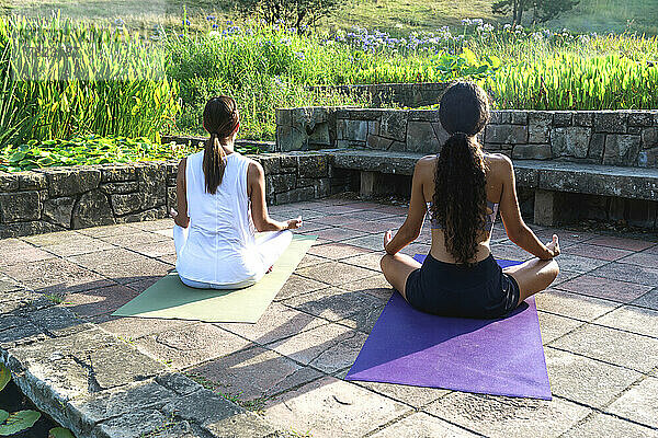 Mädchen mit Yogalehrer meditiert im Park