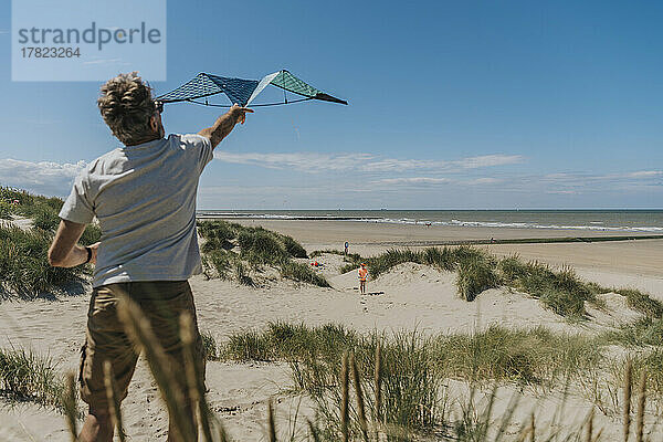 Reifer Mann lässt an einem sonnigen Tag am Strand Drachen steigen