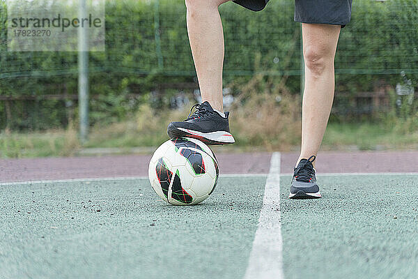 Frau mit Bein auf Fußball im Sportplatz