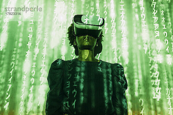 Digitaler Code fällt auf eine Frau  die einen Virtual-Reality-Simulator trägt