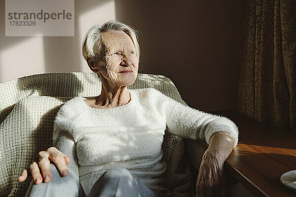 Smiling senior woman sitting on sofa at home