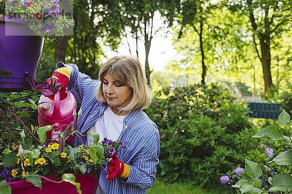 Frau gießt Blumen mit Gießkanne im Garten