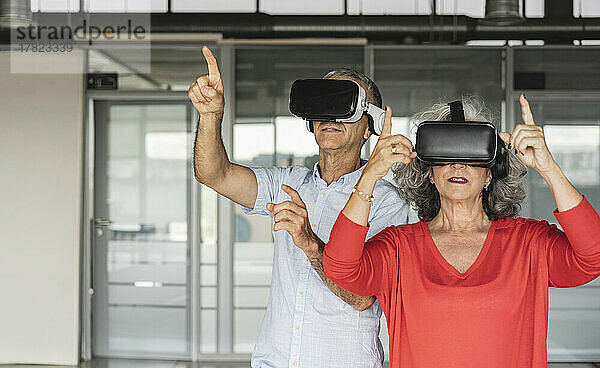 Geschäftsfrau und Geschäftsmann mit Virtual-Reality-Simulator gestikulieren im Büro