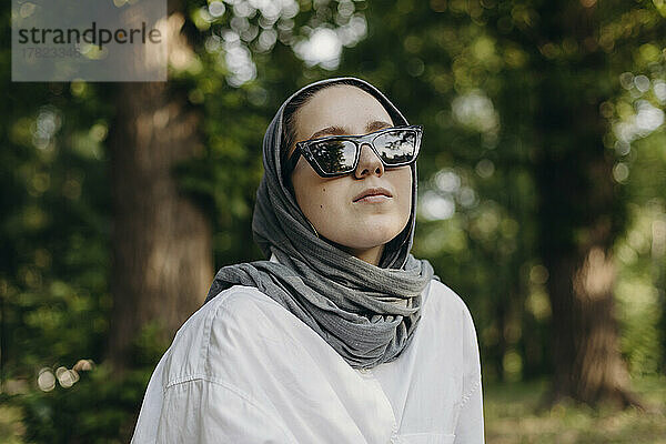 Junge Frau mit Kopftuch und Sonnenbrille im Park