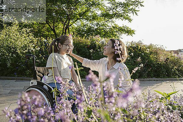 Mutter mit Mädchen im Rollstuhl im Park an einem sonnigen Tag