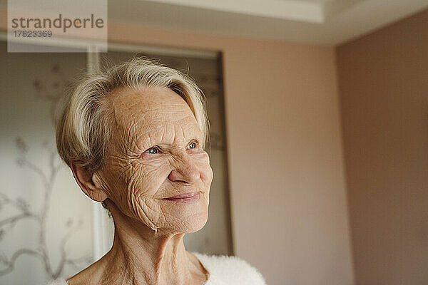 Lächelnde ältere Frau mit kurzen weißen Haaren zu Hause