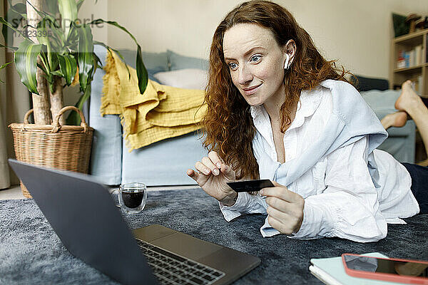 Glückliche Frau mit Kreditkarte  die zu Hause per Laptop bezahlt