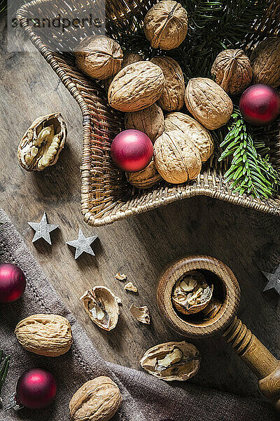 Studioaufnahme von Schneidebrett  sternförmigem Weidenkorb  Weihnachtsschmuck  Walnüssen und einfachem Nussknacker