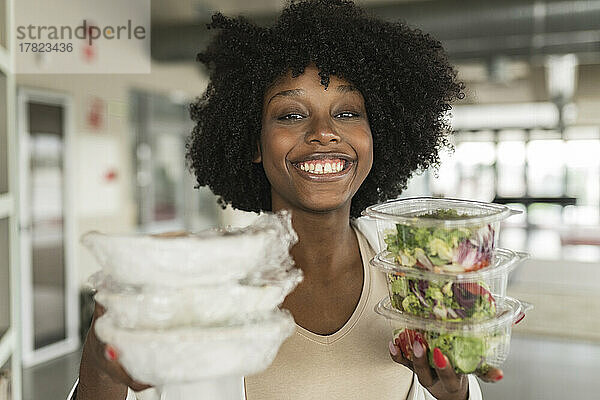 Glückliche Geschäftsfrau mit Salatboxen im Büro