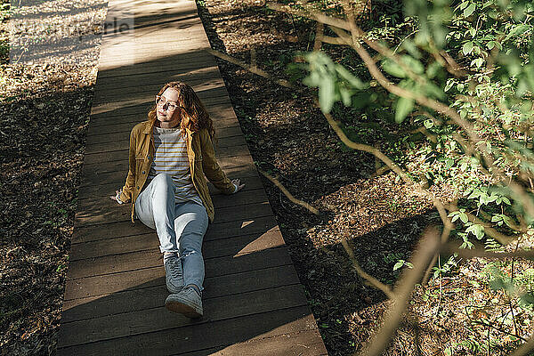Junge Frau sitzt auf Fußweg im Wald