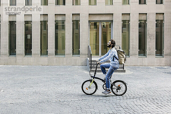 Mann mit Rucksack fährt Fahrrad auf der Stadtstraße