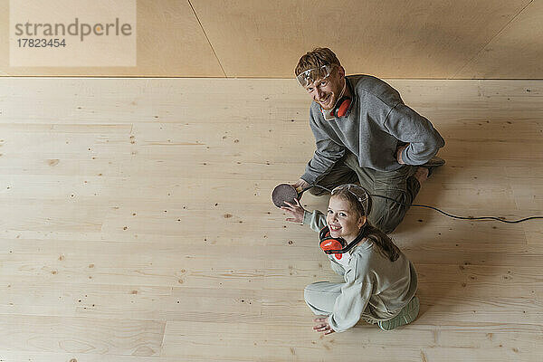 Vater und Tochter schleifen den Boden in ihrem neuen Öko-Haus