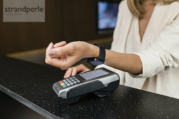 Hand einer Geschäftsfrau  die im Restaurant kontaktlos mit einer Smartwatch bezahlt
