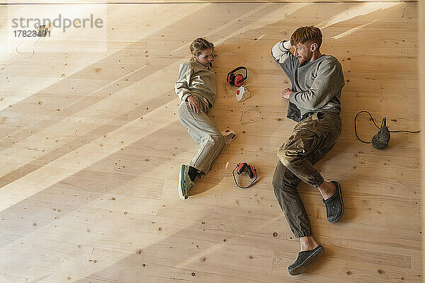 Father and daughter have rest  lying after sanding the floor in an eco house. Top view  time together